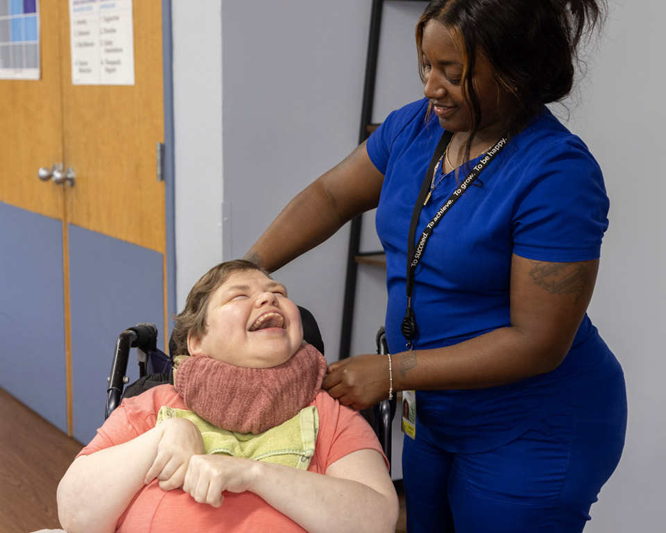 woman looking down and smiling at smiling woman in wheelchair