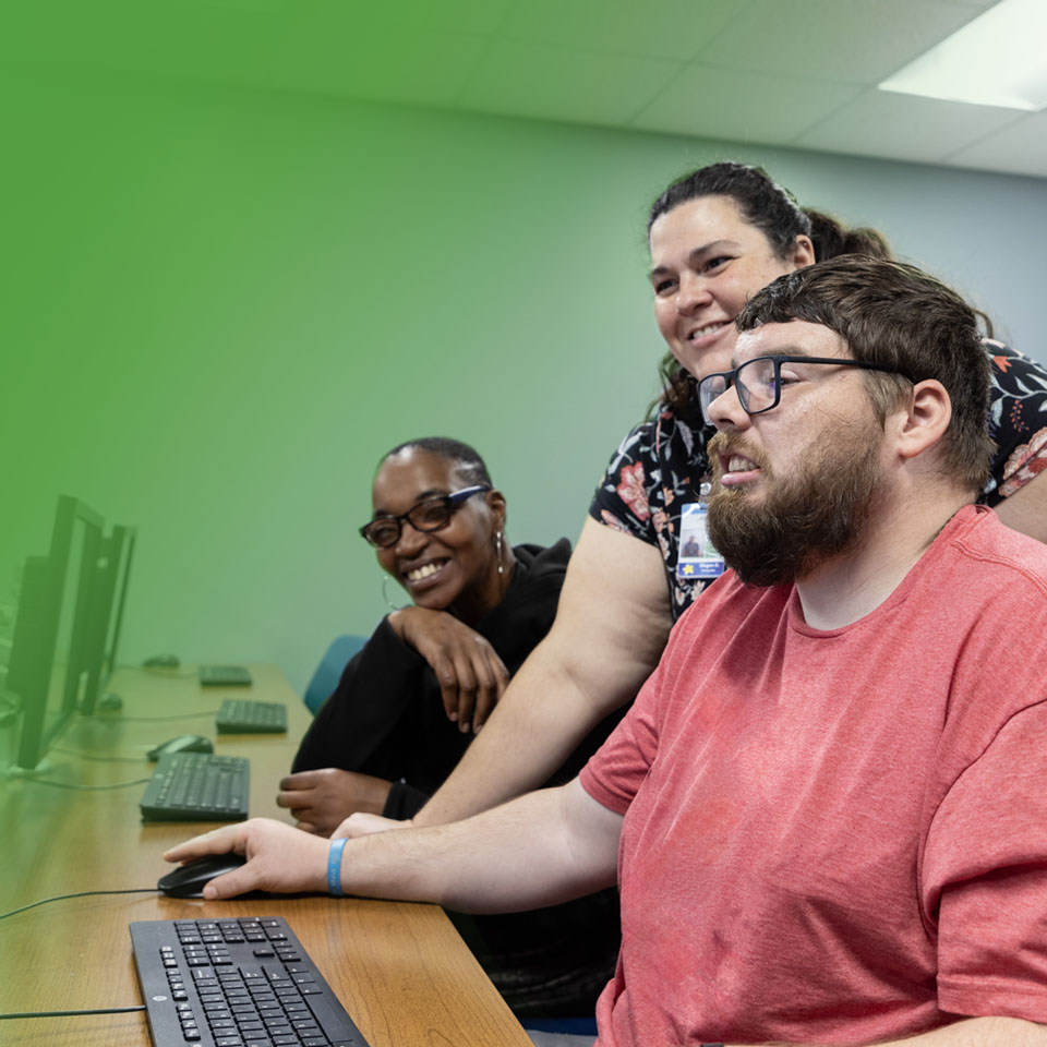 two women and a man at a computer