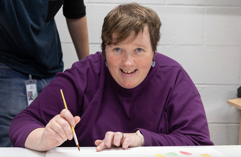 women smiling and holding a pencil