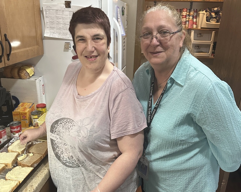 two individuals in kitchen making sandwiches